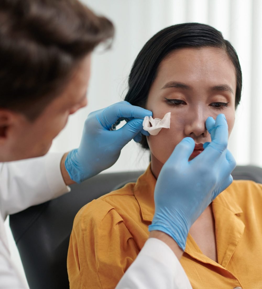 Plastic surgeon examining nose of patient after rhinoplasty