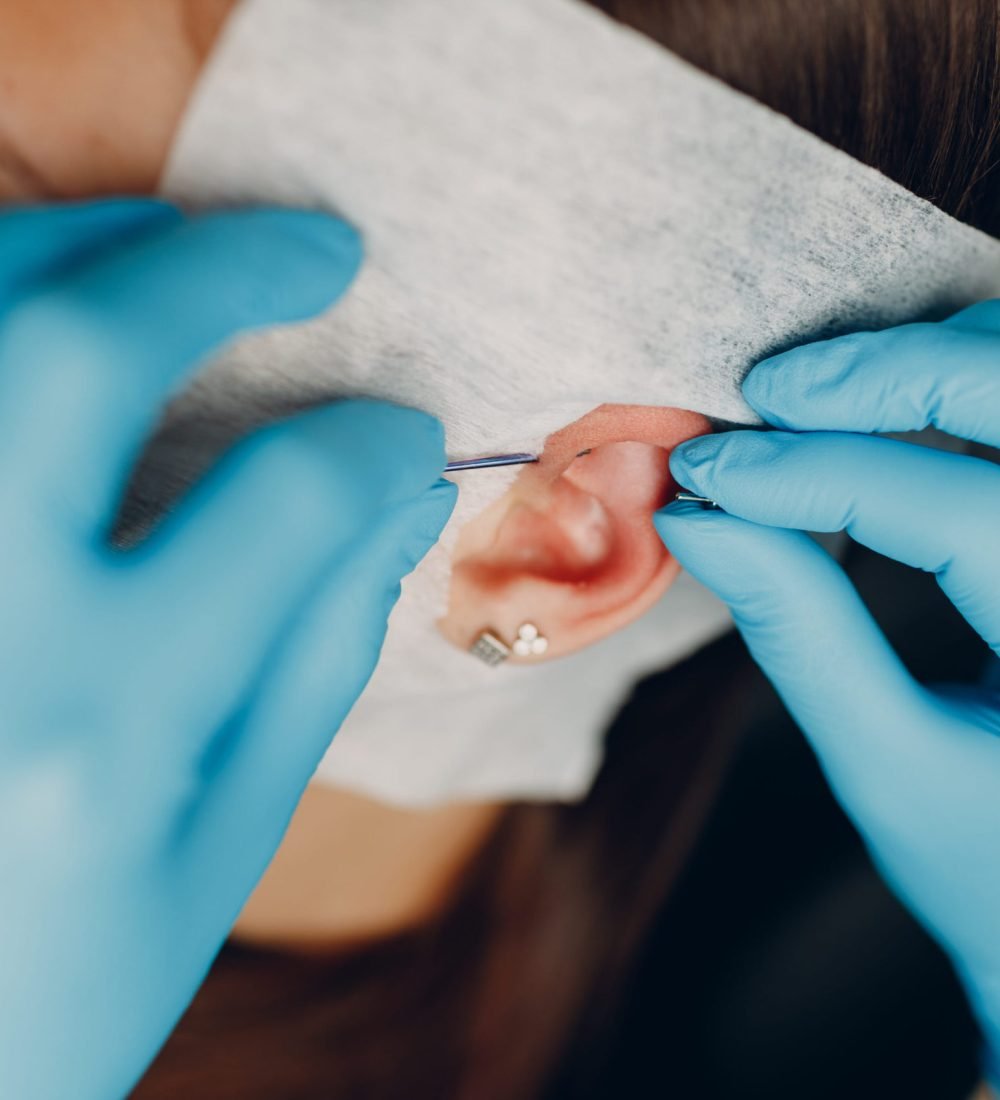 Young woman doing ear piercing at beauty studio salon